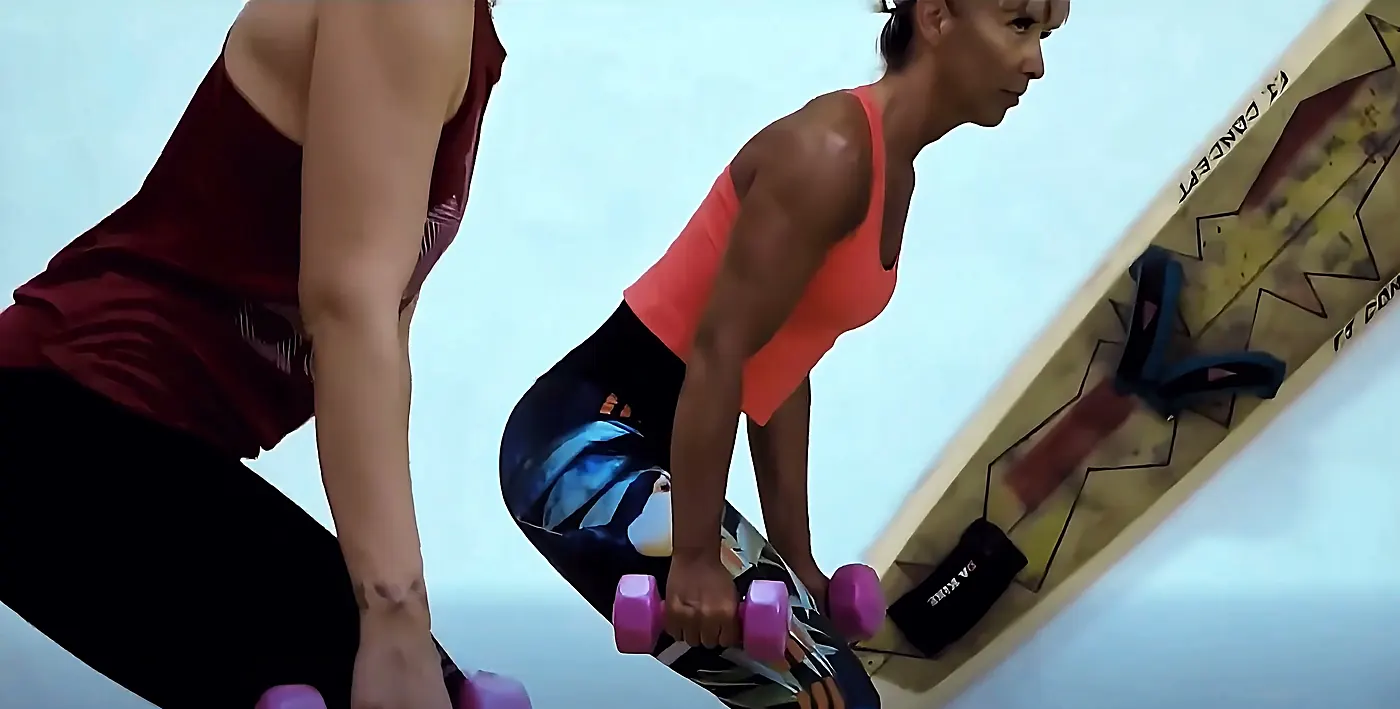 Adhérente en renforcement musculaire avec des haltères dans l’espace fitness du club